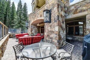 A stone exterior patio with outdoor seating, including red chairs and a glass table. - 4 Bedroom Condo (Keystone)