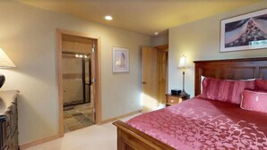 A bedroom with a bed, a nightstand, a lamp, a door, and a framed picture on the wall. - 2 Bedroom - Platinium Residence (Vail)