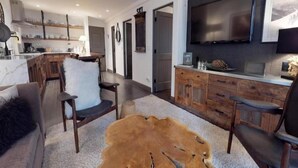 A modern living room with a large TV, wooden furniture, and a unique fur rug.