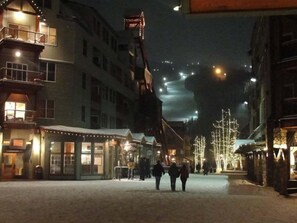 A snow-covered street with buildings on either side, including a restaurant with outdoor seating and a building with a balcony. - 1 Bedroom Condo (Keystone)