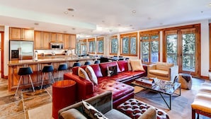 A spacious living area with a red leather sofa, a coffee table, and a kitchen with wooden cabinets and a large island. - 4 Bedroom Condo (Keystone)