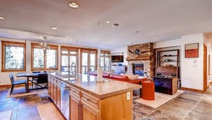 A spacious kitchen with a large island, wooden cabinetry, and a stone fireplace. - 4 Bedroom Condo (Keystone)