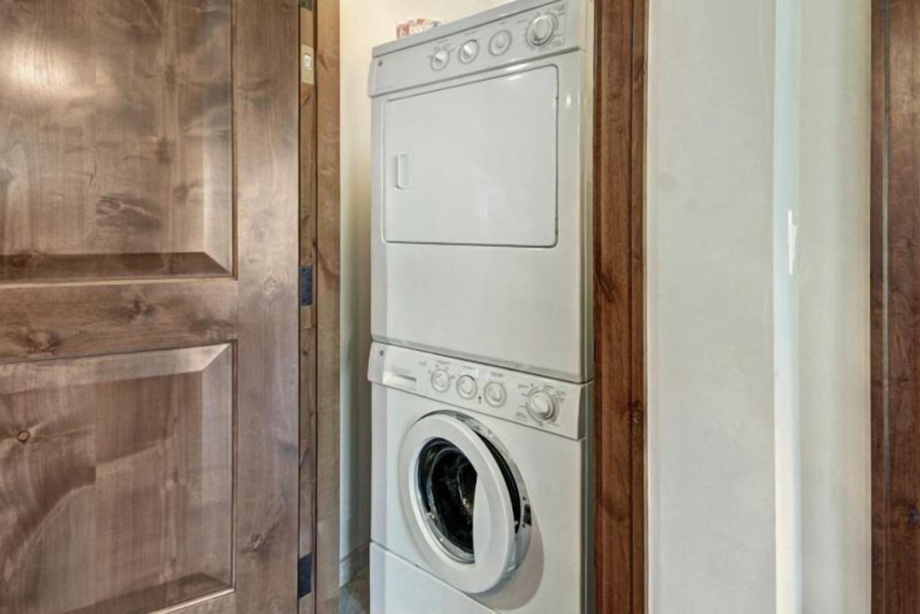 Een gestapelde wasmachine en droger in een kamer met houten lambrisering.
