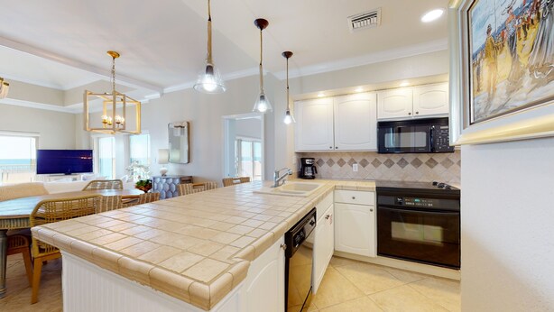 A modern kitchen with a central island, white cabinetry, a microwave, and an oven. - Beach Manor 0812 (Miramar Beach)