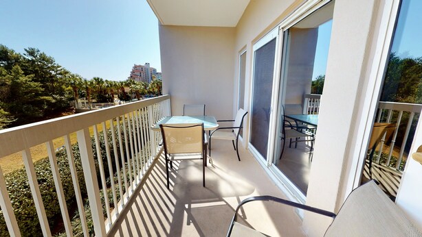 Un balcon avec une table et des chaises, une vue sur les environs et un bâtiment en arrière-plan.