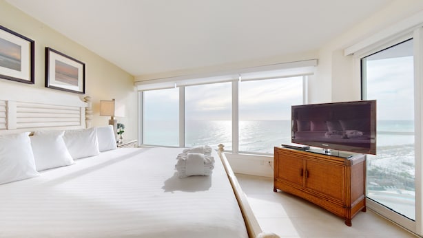 A hotel room with a large bed, a television, and a view of the ocean. - Beachside II 4291 (Miramar Beach)