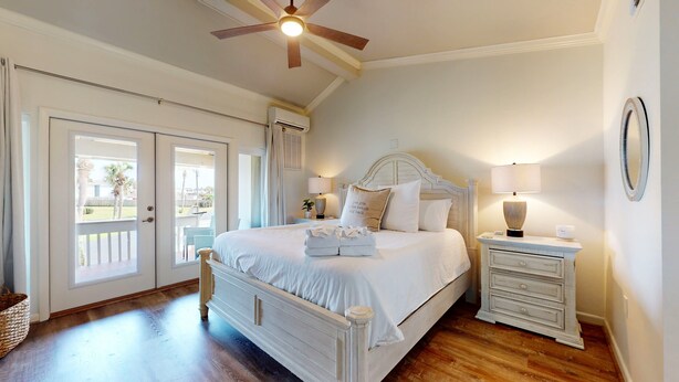 A bedroom with a bed, bedside tables, a ceiling fan, and a view through the door. - Chateau La Mer 16e (Destin)