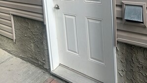 A white door with a keyhole and a peephole, a mailbox, and a small sign on the wall. - Basement suite with full kitchen  (Airdrie)