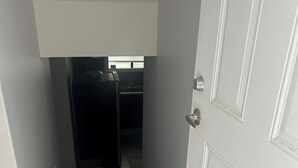 A hallway leading to a kitchen with a refrigerator and a window above the sink. - Basement suite with full kitchen  (Airdrie)