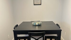 A dining table with four chairs, a decorative bowl on the table, and a framed inspirational quote on the wall. - Basement suite with full kitchen  (Airdrie)