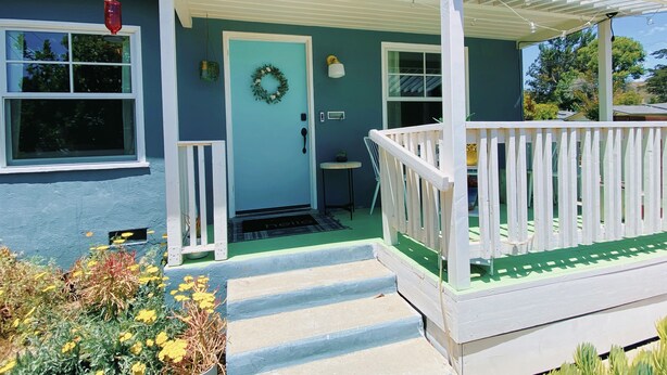 A house with a porch, a door with a wreath, and a 'hello' mat.