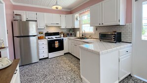A kitchen with white cabinets, a stainless steel refrigerator, a gas stove, a microwave, and a toaster.