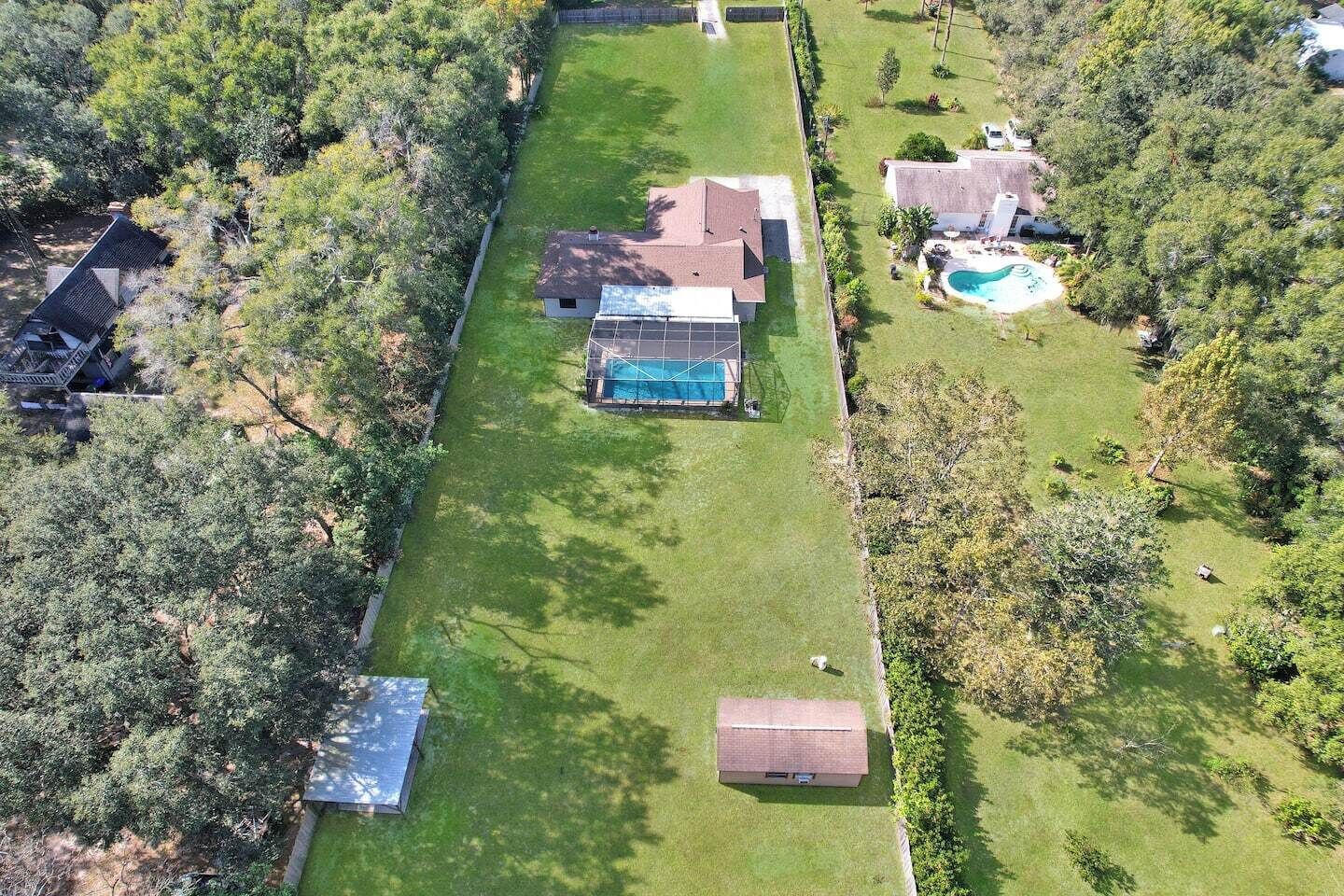 Vista aérea de una propiedad residencial con piscina, garaje independiente y césped cuidado.