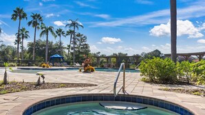 A swimming pool area with a hot tub, palm trees, and a covered seating area.