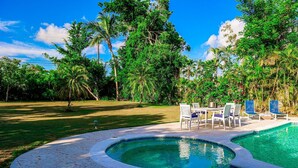 Une piscine à bordures courbes, entourée d’une terrasse dallée.