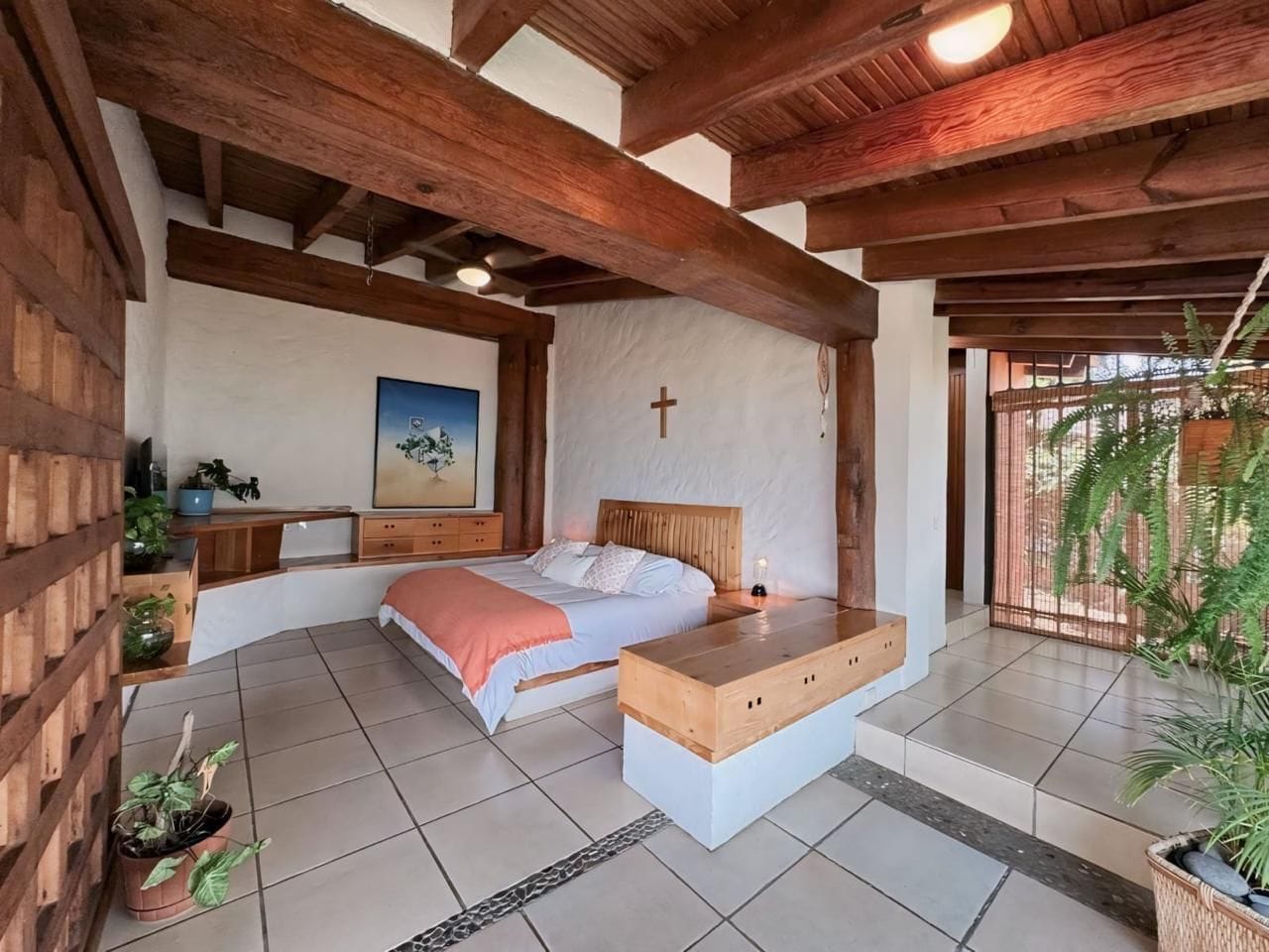 Une chambre à coucher avec un lit, une table de chevet et une croix accrochée au mur.