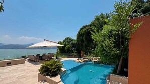 A swimming pool with a view of the sea, surrounded by lounge chairs and a covered area. - CASA EL MIRADOR-VALLE DE BRAVO (Valle de Bravo)