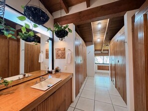 Un baño moderno con tocador de madera, un espejo grande y plantas colgantes.