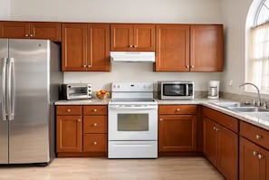Une cuisine avec des meubles de rangement en bois, un réfrigérateur en acier inoxydable, un four à micro-ondes, une cuisinière et un évier.