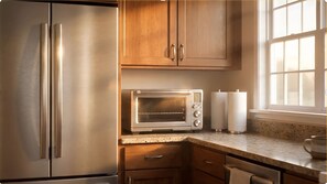 Una cocina con electrodomésticos de acero inoxidable, armarios de madera y un ventanal.
