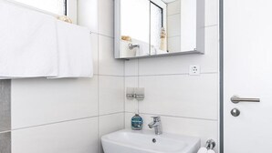 Un bagno moderno con un lavandino bianco, uno specchio e un portasciugamani.