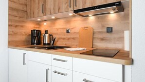 Una cucina moderna con mobili in legno, elettrodomestici in acciaio inossidabile e un piano di lavoro in legno.
