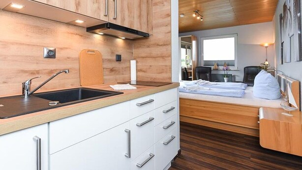 Una cucina moderna con mobili in legno, un lavello nero e un piano di lavoro in legno.