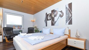 Una camera da letto moderna con un letto in legno, due comodini, una scrivania e decorazioni astratte alle pareti.