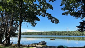 A lakeside view with a dock, a boat, and a green kayak. - MAPLE COTTAGE - Lakefront on Thayer Lake in Alden with WiFi, AC (Alden)