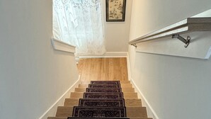 A wooden staircase with a handrail, a patterned rug at the bottom, a window with sheer curtains, and a framed artwork on the wall. - Built in 2024: 2100SF, 4-BR, 4-full-BA pet-friendly house in marvelous Apex (Apex)