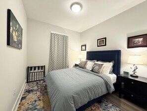Een slaapkamer met een bed, nachtkastjes, een vloerkleed met patroon en wanddecoratie.