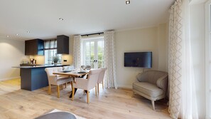 A modern kitchen with a dining area, a flat-screen TV, and a seating area with a sofa. - Modern vacation apartment for up to 4 people over two floors with terrace, sauna (Hörnum (Sylt))