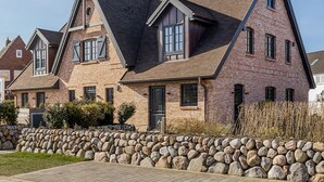 A large, two-story house with a stone facade and a steeply pitched roof. - Willkommen in Unserer Inselsuite! - Domizil Budersand 34 (Hörnum (Sylt))