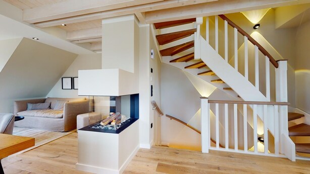 A loft-style living area with a fireplace, a staircase, and a sofa. - Willkommen in Unserer Inselsuite! - Domizil Budersand 34 (Hörnum (Sylt))