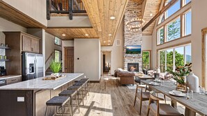 A spacious kitchen with a large island, wooden ceiling, and a stone fireplace. - Wow Wow Wow a must stay cabin! (Sevierville)