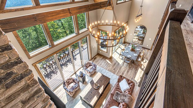 A spacious loft-style room with large windows offering mountain views, a wooden ceiling, and a central chandelier. - Wow Wow Wow a must stay cabin! (Sevierville)