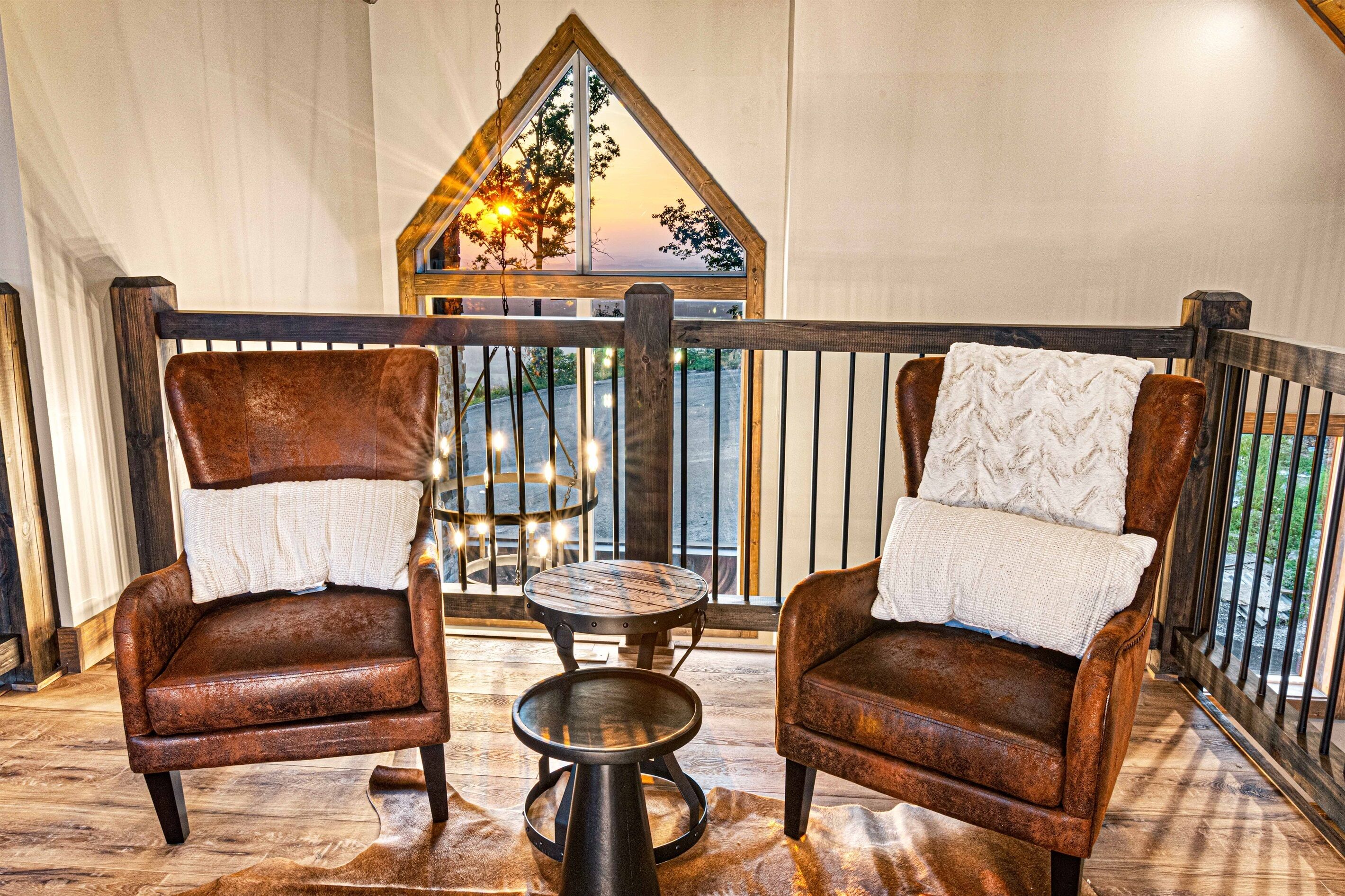 A cozy seating area with two leather chairs and a small round table, overlooking a scenic view through a triangular window.