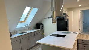 A modern kitchen with a skylight, a built-in microwave, and a large island with a sink. - Beatiful Studio in Raynham MA, minutes to shopping, Massasoit State park, etc (Raynham)