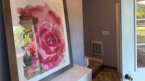A framed watercolor painting of a rose on a white dresser in a hallway with a door and a window. - Beatiful Studio in Raynham MA, minutes to shopping, Massasoit State park, etc (Raynham)