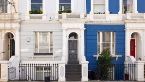 A row of terraced houses with white and blue facades, a black door, and a metal fence. - Sugared Almond - 1 bedroom apartment Notting Hill (Greater London)