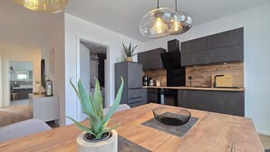 Een moderne keuken met donkere kastjes, een houten aanrecht en een hangende hanglamp.