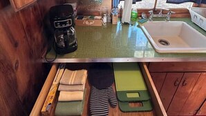 A compact kitchen with wooden cabinets, a coffee maker, a sink, and a window with curtains. - Room 5 • Desert Sanctuary  -  Downtown Joshua Tree (Joshua Tree)