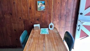 A wooden-paneled room with a table and chairs, a hanging light fixture, and a framed picture on the wall. - Room 5 • Desert Sanctuary  -  Downtown Joshua Tree (Joshua Tree)