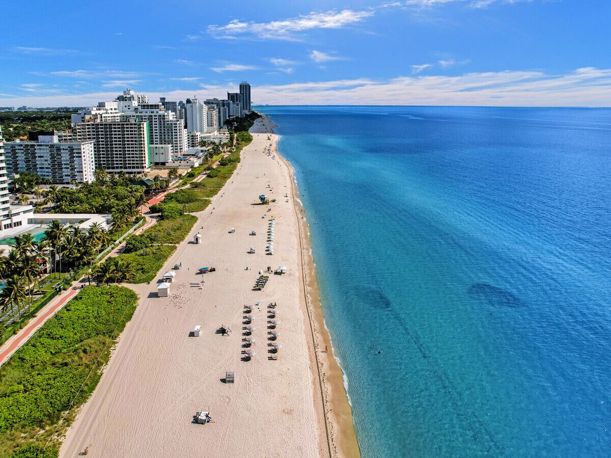 Un paisaje urbano costero con una playa amplia, edificios altos y aguas azules cristalinas.