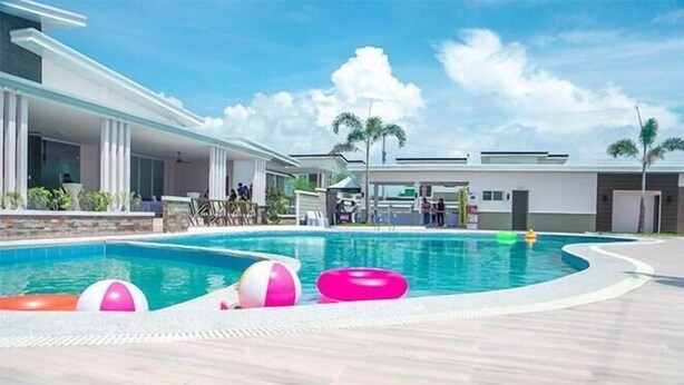A swimming pool with inflatable toys, a covered area with people, and a modern building with a flat roof. - Whole house in San Fernando (San Fernando)