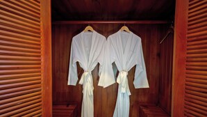 A wooden room with two white robes hanging on wooden hangers. - Villa Phum Khnar (Siem Reap)