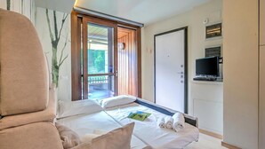 Habitación de hotel con cama, televisión, puerta y vistas al exterior.