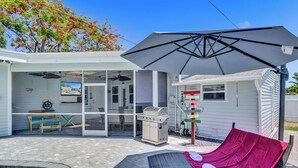 Un espace extérieur abrité comprenant une piscine, un barbecue et un hamac.