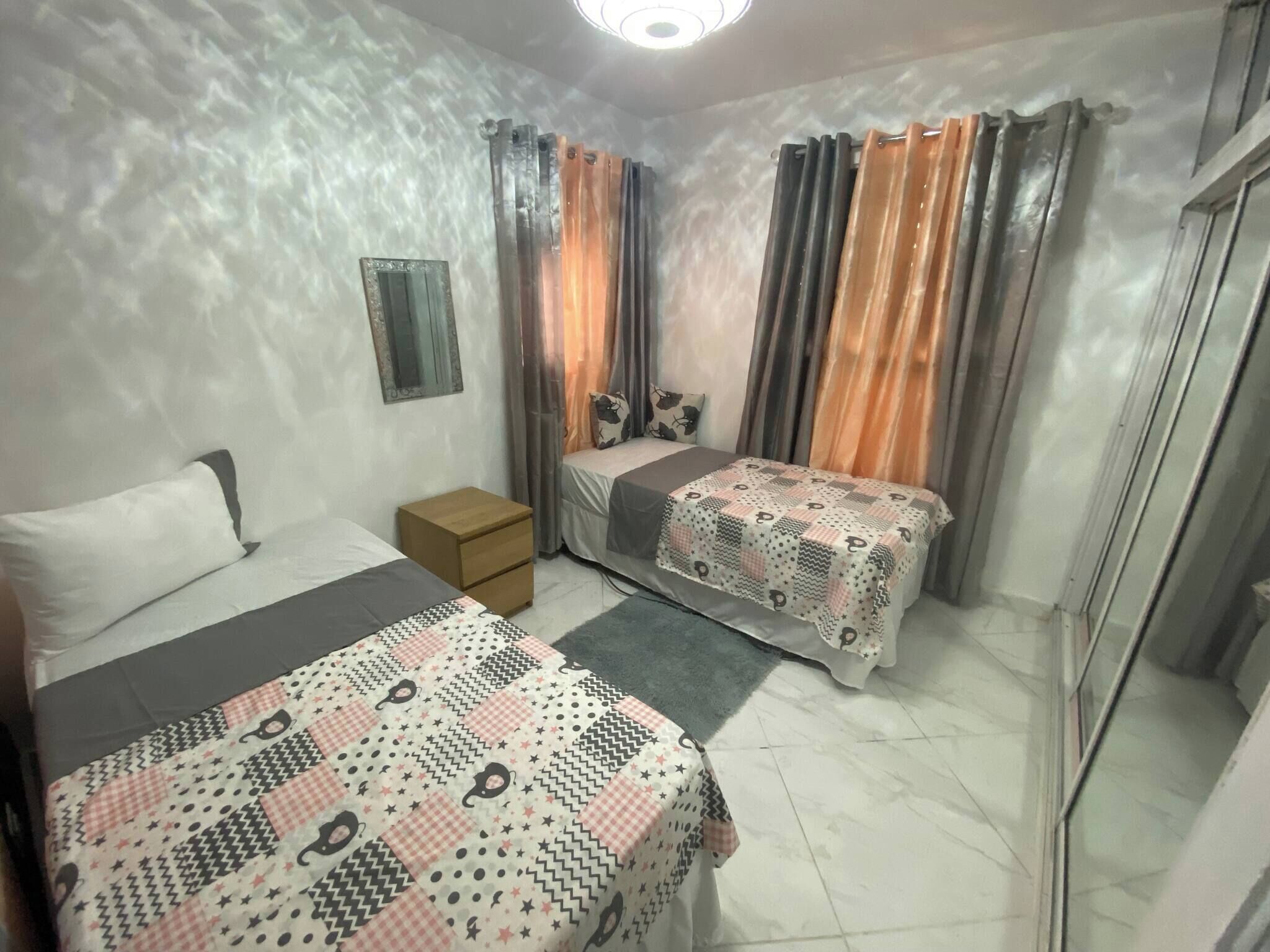 Un dormitorio con dos camas, una mesita de noche, un espejo y cortinas.