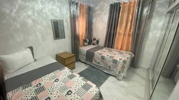 Un dormitorio con dos camas, una mesita de noche, un espejo y cortinas.